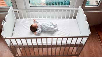 High angle view of a baby sleeping on their back in a crib.